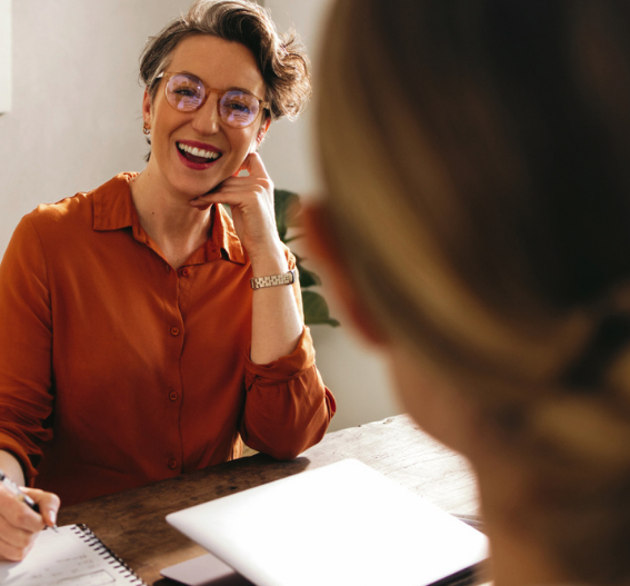 Engagerad redovisningskonsult i samtal med kund vid skrivbord. Konsulten lyssnar och ger rådgivning i en trygg och personlig miljö.
