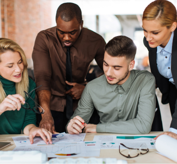 Medarbetare samarbetar kring rapporter och diagram vid skrivbord, som illustrerar samarbete och helhetsansvar inom redovisning och lönehantering.