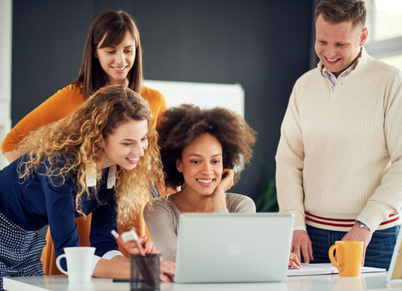 Team samarbetar framför dator på kontor, som visar samarbete och helhetsperspektiv inom redovisning och ekonomiarbete.