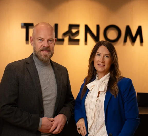 Två rådgivare framför Talenoms logotyp på kontor, symboliserar personlig service, ekonomisk rådgivning och stöd till företagets utveckling.